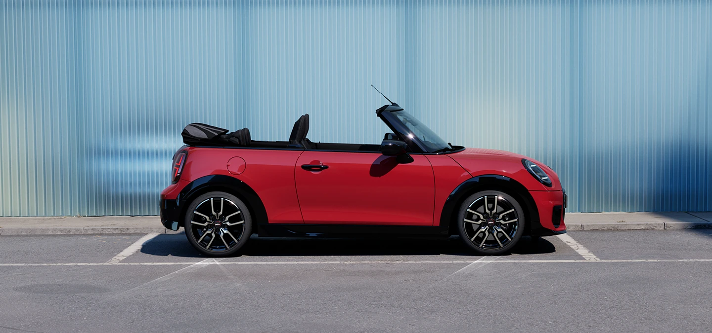 側面視角Chili Red車色的MINI Cooper敞篷車停靠在街道上。