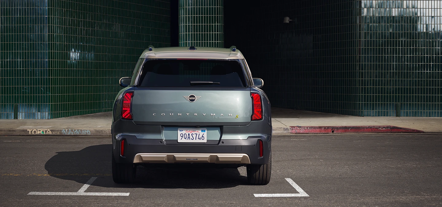 純電MINI Countryman（Smokey Green車色搭配Vibrant Silver車頂）停車狀態後視圖。